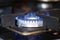 Gas burner on stove with blue fire at home closeup