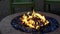 Gas or propane powered circular fire pit with blue rocks and relaxing chairs