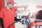 Gas station attendant in red uniform holding a fuel petrol pump nozzle against for filling up the car with petrol at gas station