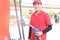 Gas station attendant in red uniform holding a fuel petrol pump nozzle against at gas station