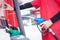 Gas station attendant in red uniform holding a fuel petrol pump nozzle against at gas station