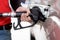 Gas station worker in red uniform filling up bronze pickup truck tank. Closeup hand holding black gas pump nozzle