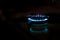 Gas stove burner with blue flame with reflection in the dark, copy space, blurred background. gas crisis