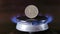 gas stove burner with russian ruble standing vertically on top, burning natural gas with blue flame