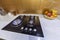 Gas stove flame burner close-up, bowl with fruit on marble counter. Luxury modern fitted kitchen with all appliances interior and