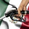 Gasoline consumption concept - Hand holding hose against flag of Mexico