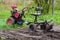 Gasoline cultivator with plow makes furrow in soil for plantation