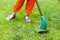 Gasoline lawn trimmer mows juicy green grass on a lawn on a sunny summer day. Close-up selective focus image. Garden equipment. Yo