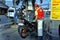 Gasoline station employee refills the fuel tank of a motorcycle for a customer