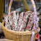 Gastronomic products for gourmets, traditional italian salami in wicker basket close-up. Real scene in market.