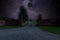 Gate and access road to the residence at night, shrouded in darkness. In the center of the frame, a black celestial body absorbs c