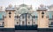 Gate iron entrance of an old blue baroque building with lawn, decorative tree and boxwood bushes, Mariinsky Palace in Kiev,