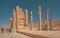 Gates with columns and impressive ruins to abandoned city and tourists walking past monuments. Persepolis
