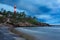 Gathering storm on beach and lighthouse on sunset