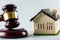 gavel closeup, striking down near a small house model real estate law