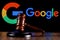 Gavel on table against the background of Google technology company logo