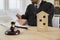 Gavel and a toy house on a table in court, with a judge working in the background