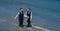 Gay grooms walking together on sea beach during Wedding day. Romantic men in sea water. Happy gay couple on wedding