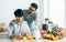 Gay LGBT sweet Asian couple wearing pajamas, smiling, looking each other, hugging with happiness and love while making breakfast