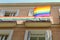 Gay pride flag backlit by sun on the facade of building downtown Madrid, Spain in lgbt friendly district Chueca