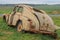 GAZ M20 Pobeda car dented, rusty and with the hood torn off in the field