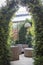 Gazebo in  garden. Arch of thuja branches. Wooden modern chairs and table. Shade