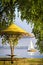 Gazebo surrounded by tree golden branches on the bay with sailing yacht on the horizon. Autumn landscape, sunny day.