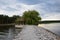 Gazebo under a large tree on the shore of a lake with a rocky embankment