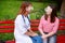 Gdpr, conversation. caring doctor or nurse taking young patient outdoors, sitting on a bench