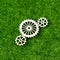 Gears made of wood on the background of artificial green grass.