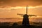 Geese flying against the sunset on the Dutch windmill