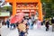 Geishas girl wearing Japanese kimono among red wooden Tori Gate at Fushimi Inari Shrine in Kyoto, Kimono is a Japanese traditional