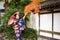 Geishas girl wearing Japanese kimono among red wooden Tori Gate at Fushimi Inari Shrine in Kyoto, Kimono is a Japanese traditional