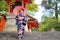 Geishas girl wearing Japanese kimono among red wooden Tori Gate at Fushimi Inari Shrine in Kyoto, Kimono is a Japanese traditional
