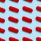 Gel capsule seamless pattern. Red capsule drug, pharmacy concept. food supplement, on light blue