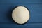 Gelatin powder in bowl on blue wooden table, top view