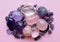 Gemstone minerals on a pink background. Round tumbling amethyst minerals, amethyst crystal and rose quartz