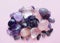 Gemstone minerals on a pink background. Round tumbling minerals amethyst, amethyst druse and rose quartz