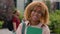 Gen z happy African American smiling student girl holding book textbook glad woman female schoolgirl in city university