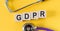 General Data  Protection Regulation. Word GDPR building from wooden cubes on yellow desk with stethoscope