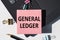 GENERAL LEDGER note is written on a paper sticker on a laptop keyboard