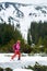 General side view of young female backpacker skier in pink suit ski touring, exploring winter mountains and skiing up