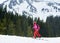 General side view of young female backpacker skier in pink suit ski touring, exploring winter mountains and skiing up