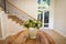 General view of house interior with table and vase with flowers in spacious hallway and staircase