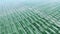 General view of industrial greenhouses abstaract panorama aerial flight, green sprouts, sky reflected in clean glasses