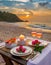 Generated imageSummer love. Romantic sunset dinner on the beach. Table honeymoon set for two with luxurious food