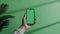 Generative AI. Hand Holding a Smartphone With Green Screen Against a Plain Green Background