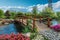 Generative AI Image of River with Wooden Bridge in Garden with Flowering Plants in Spring