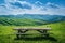 Generative AI Image of Wooden Picnic Table in the Meadow with Hills View in Bright Day