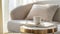 Generative AI White cup and book on two modern gold coffee tables and stylish armchair with decorative pillow in t